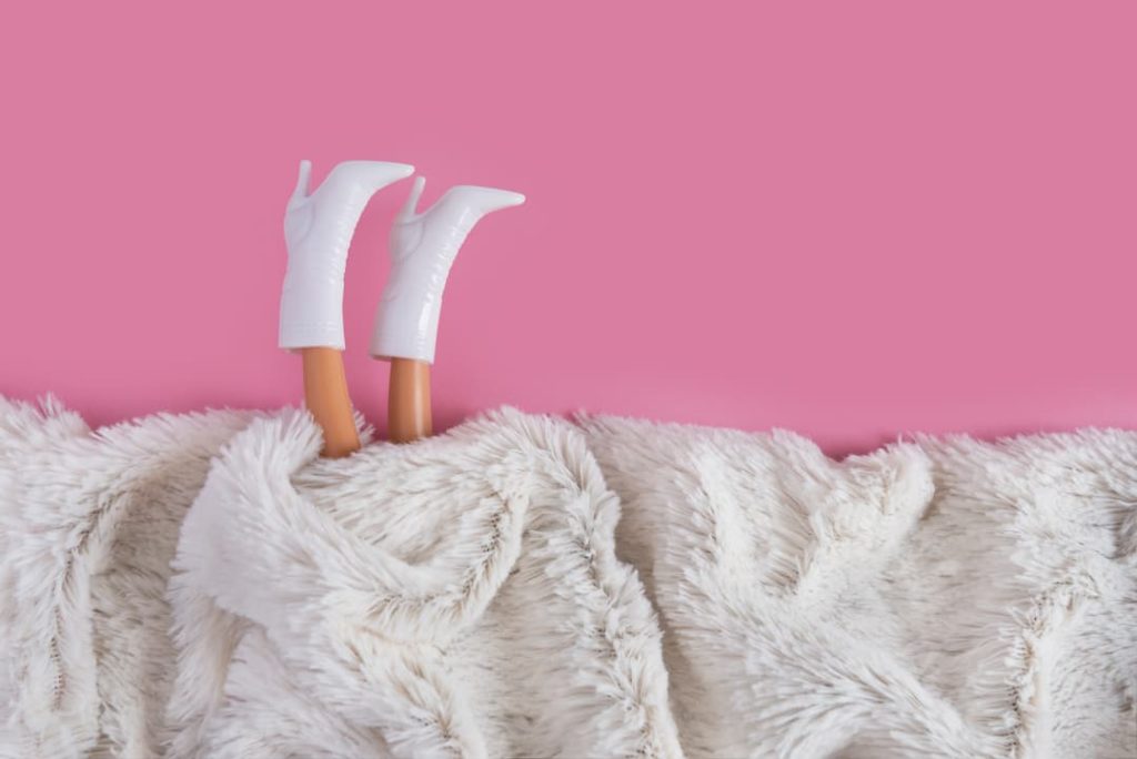 Barbie Legs Sticking Out From White Fur On A Pink Background