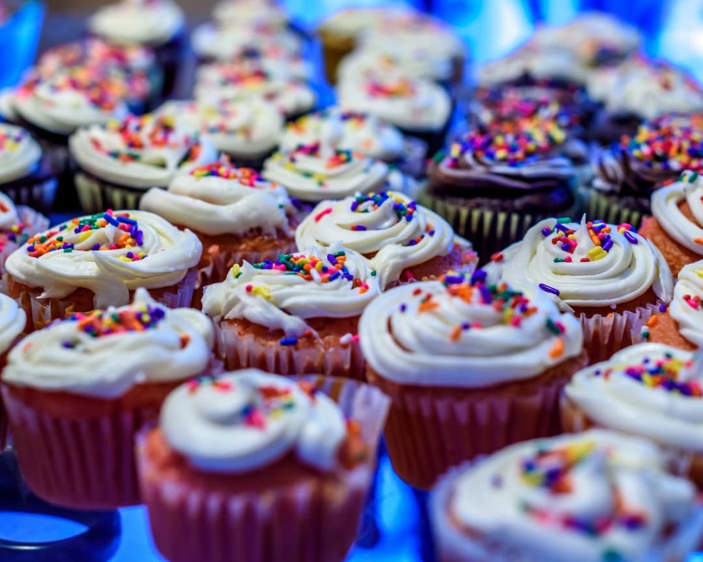 A Close Up Of Cupcakes With Sprinkles On A Blue Background